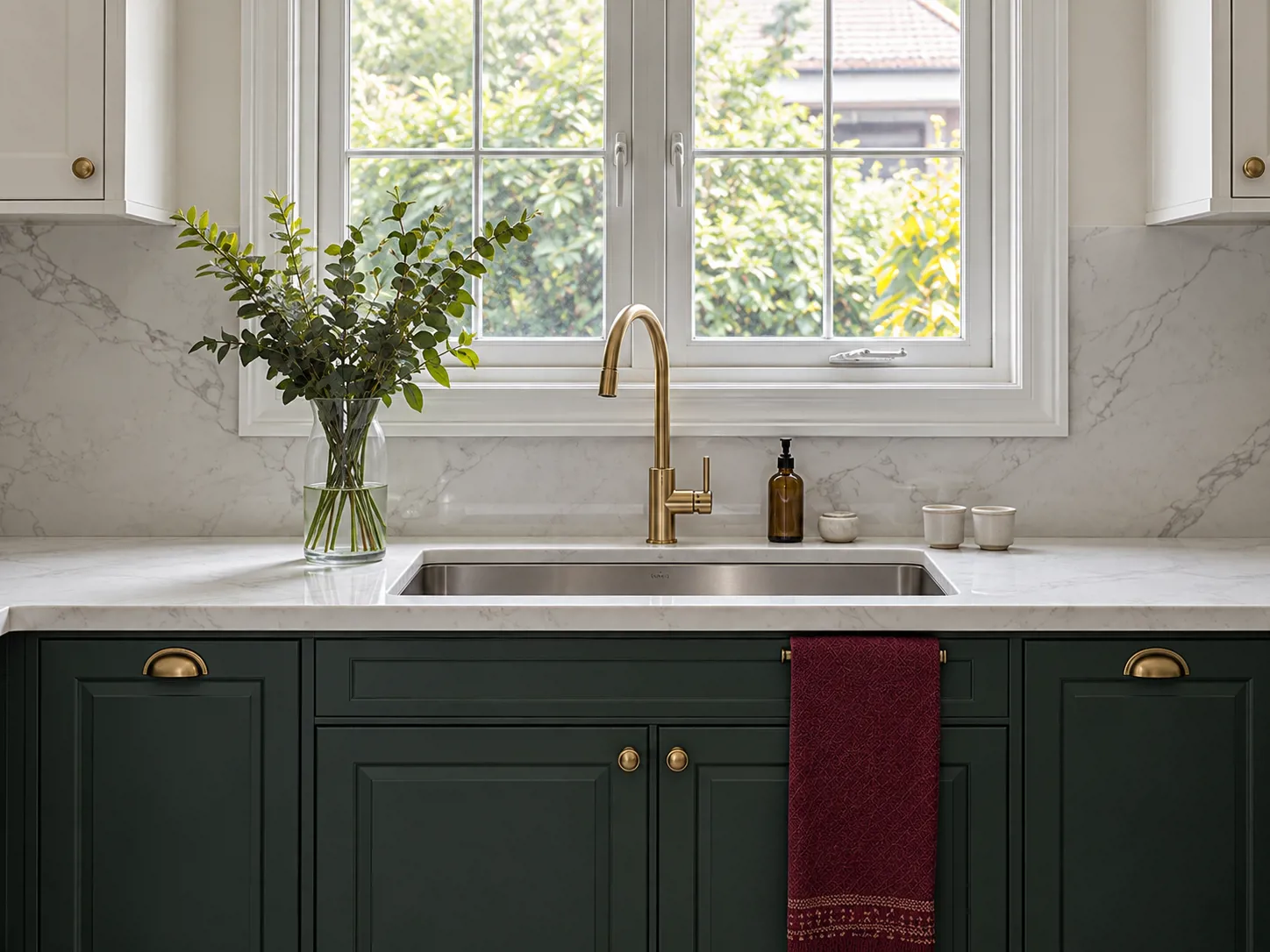 Sink undermount stainless di depan jendela menyatu dengan quartz putih, memberi area cuci tanpa bibir bak di atas meja.